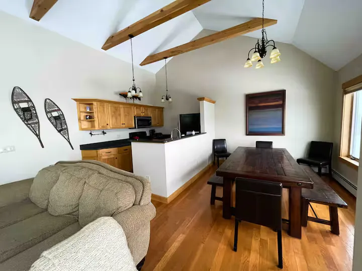 A cozy living room with wooden floors, a dining table, and a kitchen area.