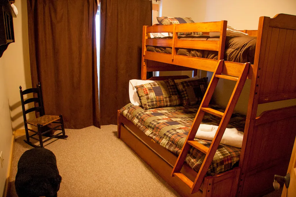 Bunk bed with ladder in a room with brown curtains.